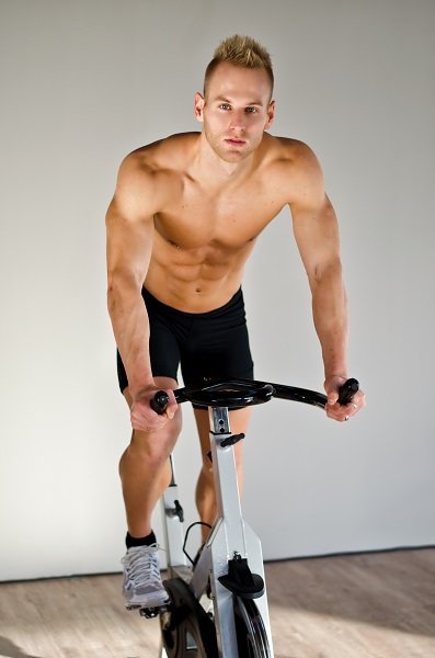Handsome young man doing spinning on bike