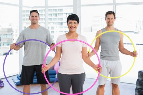 Portrait of fitness class holding hula hoops in bright gym