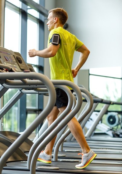 man with smartphone exercising on treadmill in gym