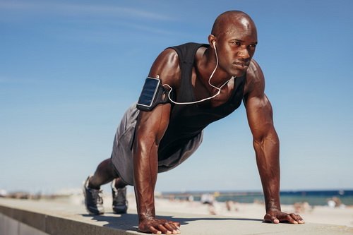 Muscular man doing push ups against blue sky