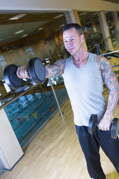 young man making front raises - workout routine