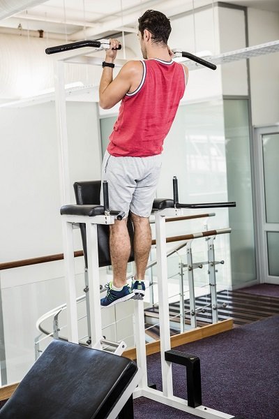 Muscular man doing pull up in a gym