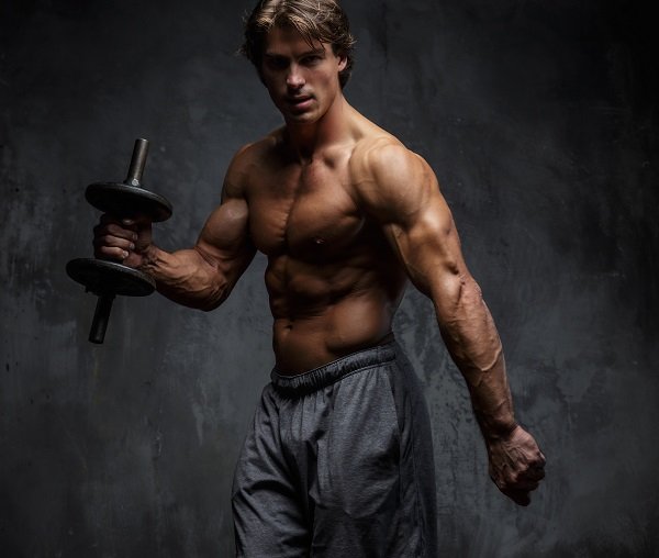 Shirtless muscular man doing biceps workout.