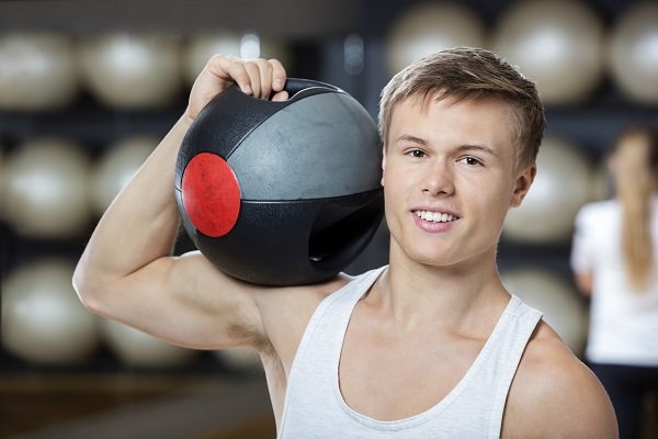 Man Keeping Medicine Ball On Shoulder In Gym