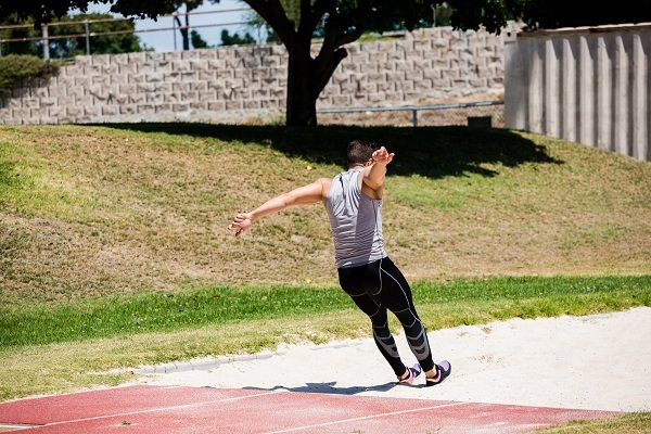 Rear view of athlete performing a long jump during a competition